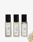 Three Reimi Botanical Perfume Oil bottles on a white surface with a tiled wall background