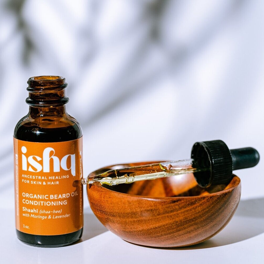 Ishq organic beard oil bottle with wooden bowl and dropper on a light background
