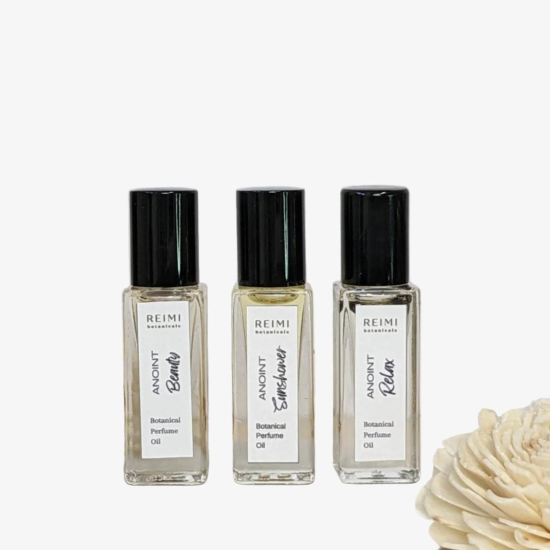 Three Reimi Botanical Perfume Oil bottles on a white surface with a tiled wall background
