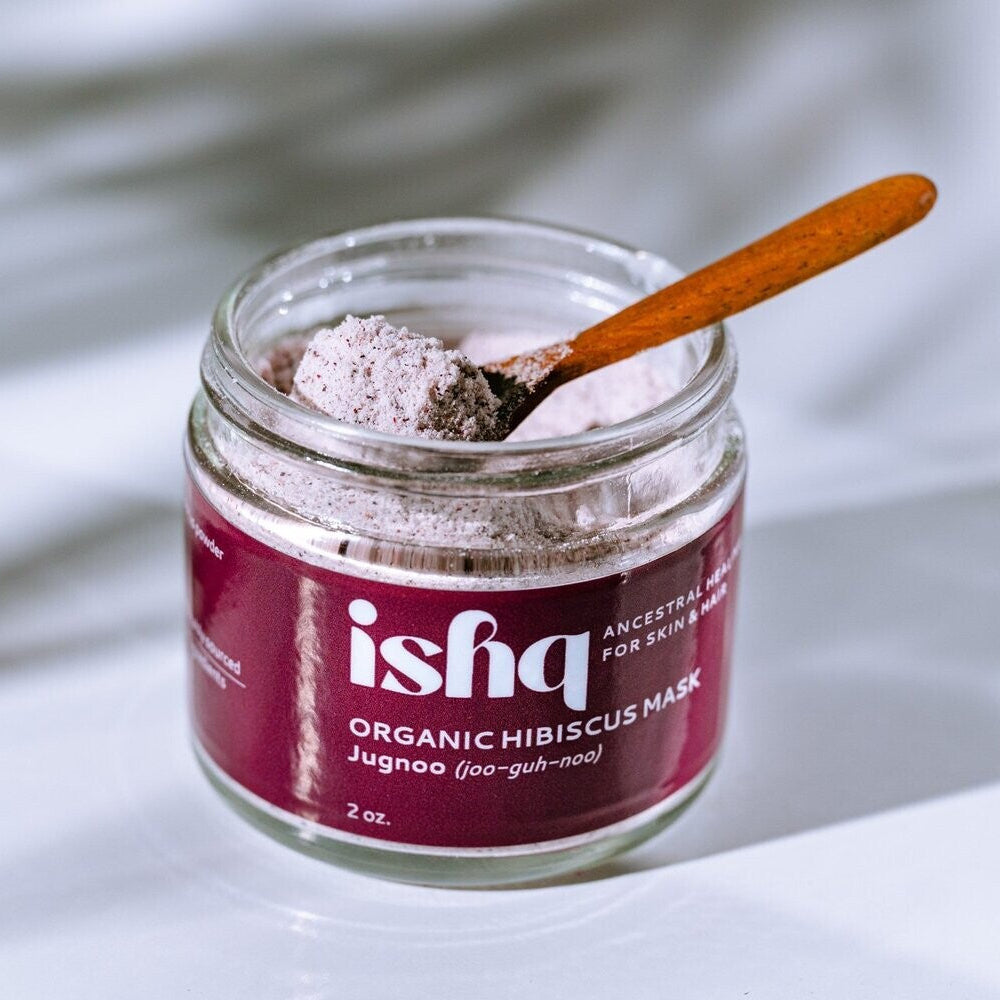 Jar of 'ishq' organic hibiscus mask with a wooden spoon on a light background