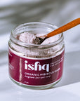 Jar of 'ishq' organic hibiscus mask with a wooden spoon on a light background
