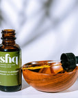 Isha organic cleanser bottle with dropper and wooden bowl on a light background